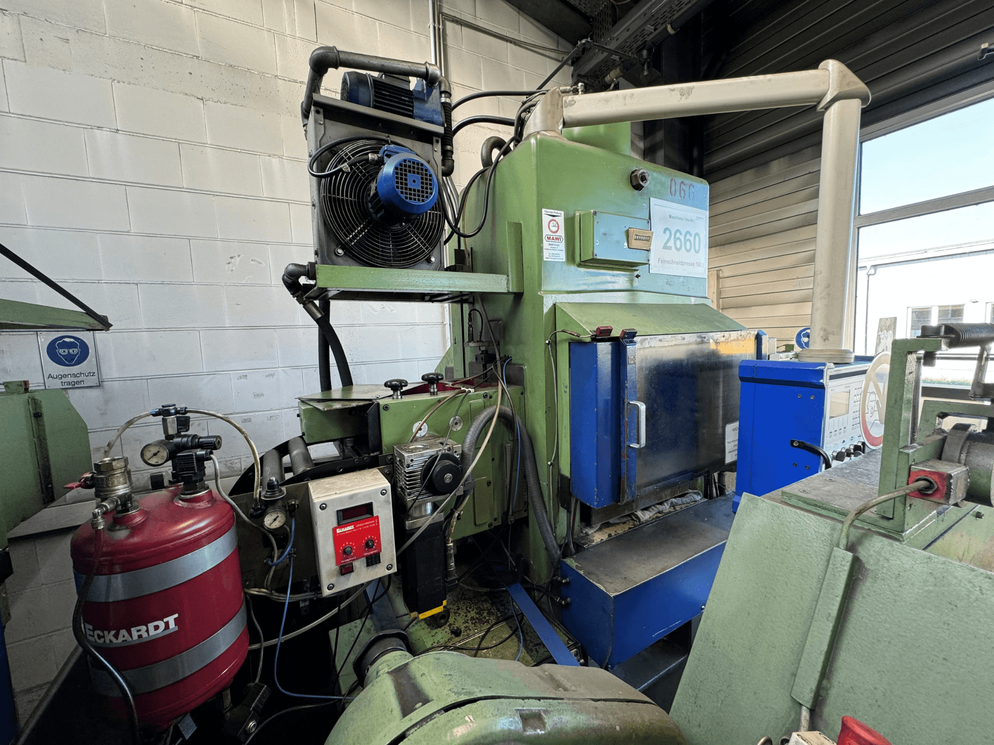 Industrial machine featuring a fan, control panel, and red fuel tank; viewed from the front in a workshop setting.